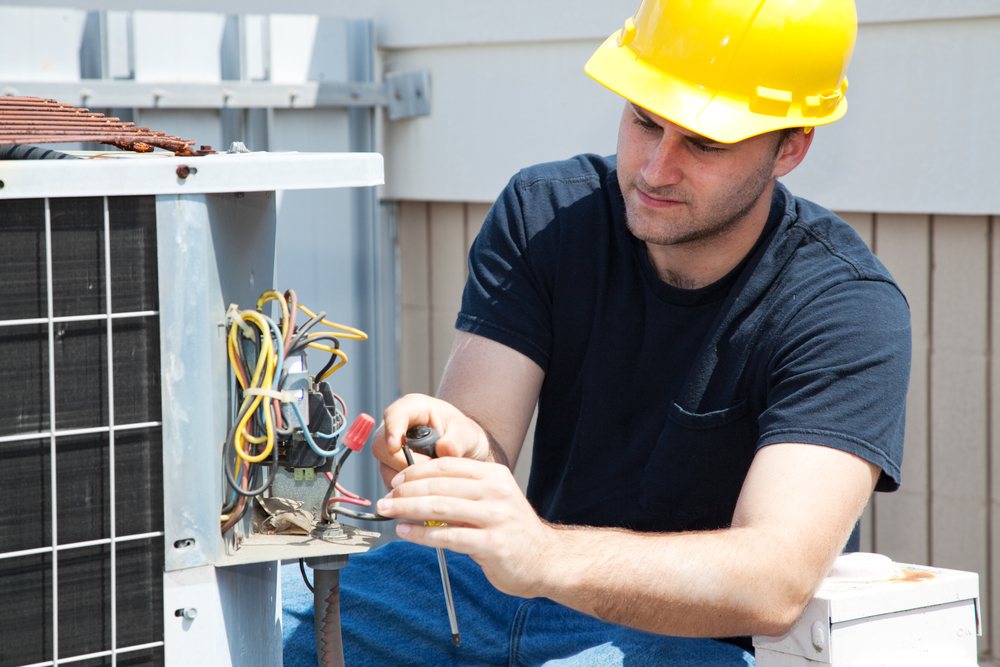 Young,repairman,fixing,an,industrial,air,conditioning,compressor.